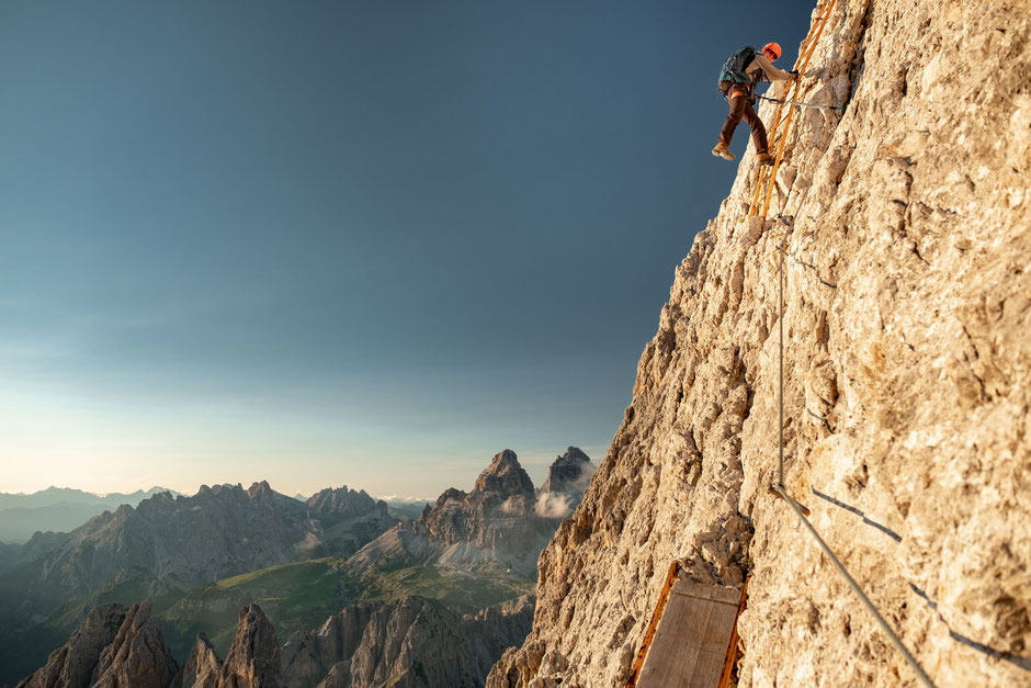 Climber on a vertical ladder on via ferrata Merlone in the Italian Dolomites. 