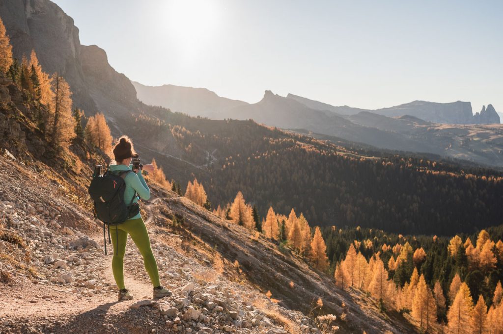A hiker taking a picture of the views on the third stage of the Sassolungo Circuit hike in the Italian Dolomites